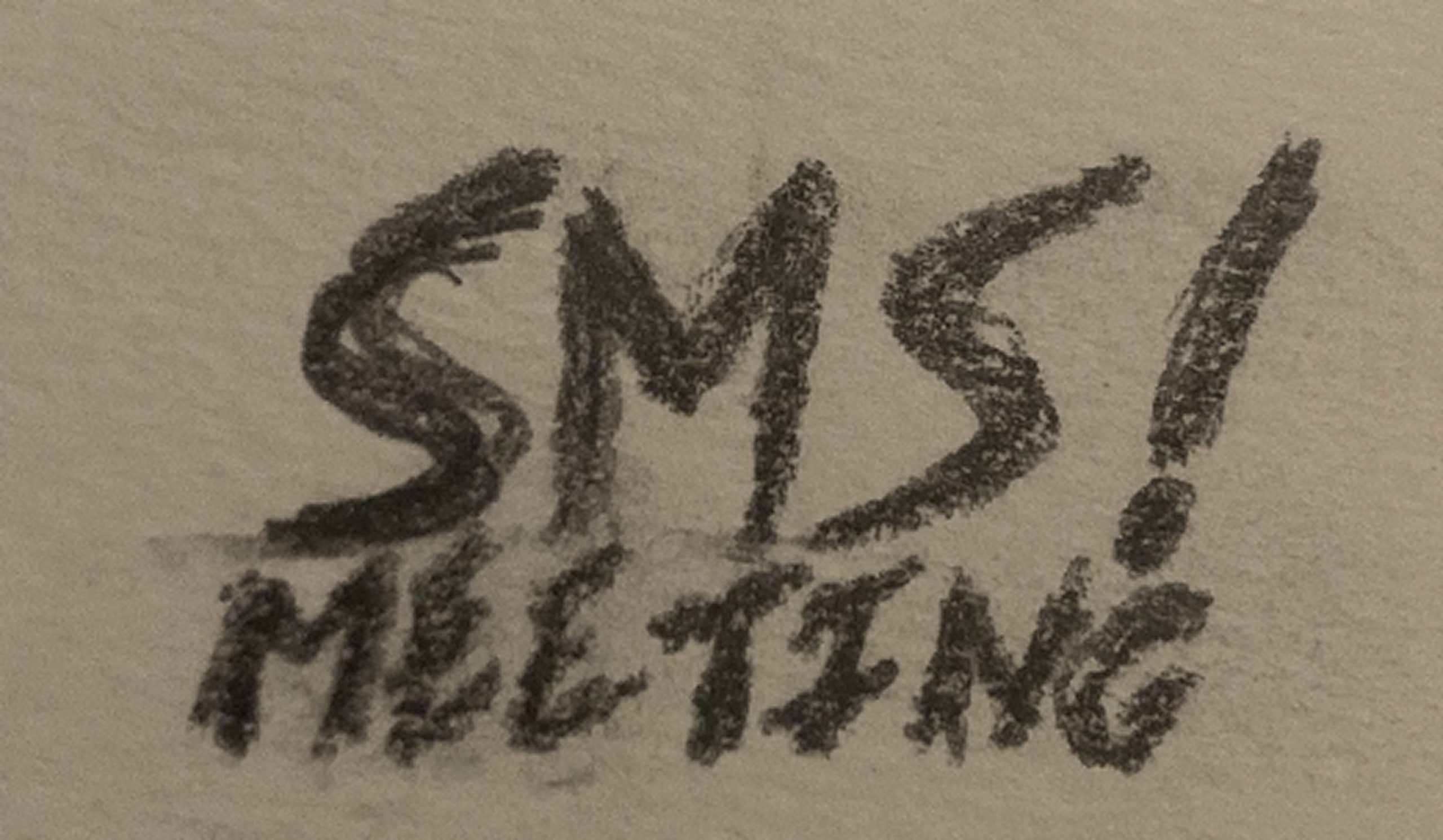 Photographie d’un croquis au crayon : « SMS! MEETING » tracé à la main sur du papier, exploration de la piste typographique.